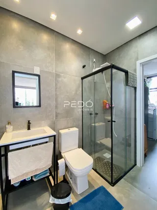 Foto de um banheiro com piso cerâmico e box de vidro.