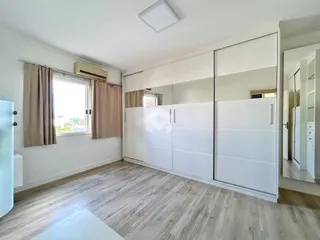Ambiente interno com piso de madeira e armários embutidos brancos.