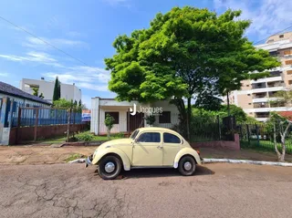 Um carro amarelo está estacionado em uma rua com árvores grandes.