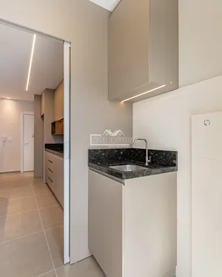 Cozinha moderna com armários brancos e bancada escura.