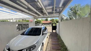 Vista externa de uma propriedade com parede branca e estrutura de cobertura.