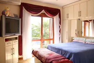 Foto de um quarto com cama e cortinas em uma residência.