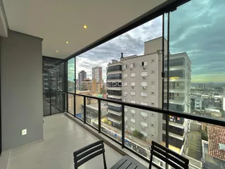 Vista panorâmica de um apartamento com grandes janelas que oferece uma vista da cidade.
