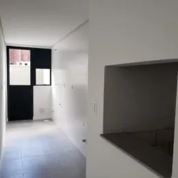 Corredor interno com paredes brancas e piso claro.