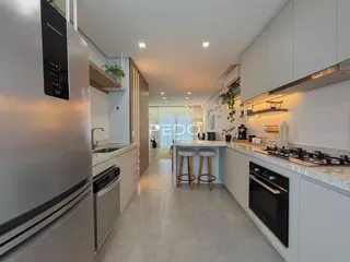 Cozinha moderna com armários brancos e bancadas claras em um imóvel no Brasil.