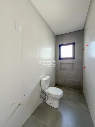 Corredor interno com piso de cerâmica e um vaso sanitário.