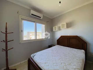 Quarto com janela e cabeceira de madeira em um imóvel no Brasil.