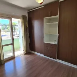 Sala de estar com piso de madeira e parede em tom marrom escuro.