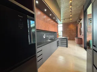 Vista interna de uma cozinha moderna com revestimento de madeira e parede de tijolos aparentes.