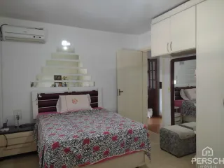Quarto com cama e armários brancos em um imóvel.