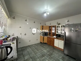 Foto interna de uma cozinha com armários de madeira e geladeira moderna.