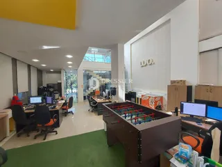 Imagem de um espaço de escritório moderno com mesas de trabalho e uma mesa de jogos.
