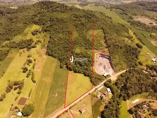 Vista aérea de uma propriedade rural com áreas de vegetação e campos.