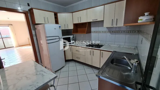 Vista interna de uma cozinha com armários e eletrodomésticos.