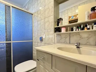 Foto de um banheiro com azulejos brancos e louças sanitárias.
