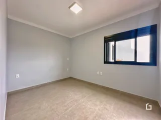 Ambiente interno de uma sala vazia com piso de cerâmica e parede branca.