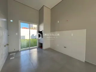 Interior de um ambiente com paredes brancas e piso de concreto em uma residência.