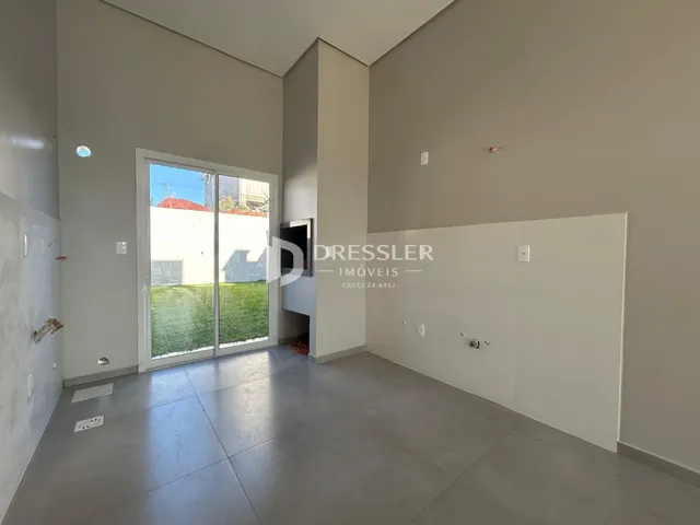Interior de um ambiente com paredes brancas e piso de concreto em uma residência.