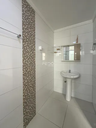 Banheiro com revestimento de azulejo e piso branco.