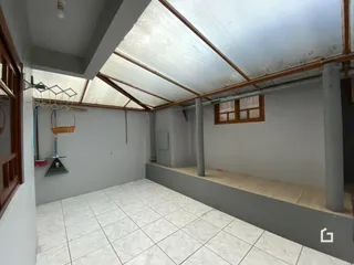Imagem de uma área interna com piso de cerâmica e estrutura de teto inclinada.