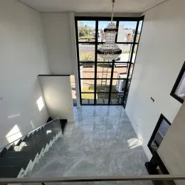 Hall de entrada com piso claro e porta de vidro que dá para o exterior.