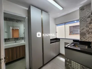 Uma cozinha moderna com armários em tom cinza e bancada escura.