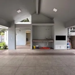 Hall de entrada com piso de concreto e estrutura de teto exposta.