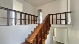 Vista de um corredor com escadaria de madeira.