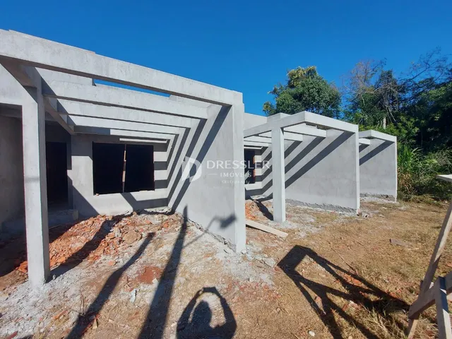 Fachada de uma construção com estrutura de concreto exposta no solo seco.