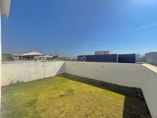 Vista de um quintal gramado cercado por um muro branco.