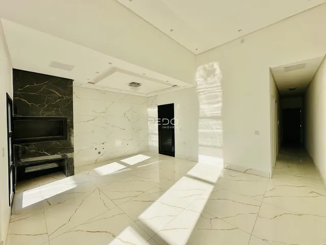 Ambiente interno de uma sala de estar com piso de mármore claro e paredes brancas.