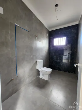 Foto de um banheiro interno com piso de cerâmica e paredes em tons de cinza.
