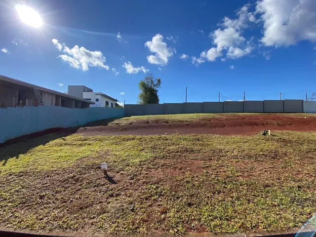 Foto de um terreno aberto com grama seca e cerca no fundo.