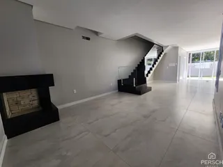 Sala de estar ampla com lareira e piso de porcelanato em um imóvel em Lajeado.