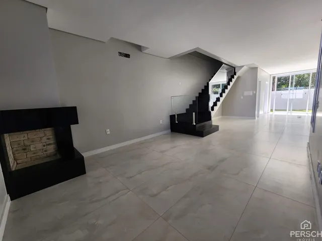 Sala de estar ampla com lareira e piso de porcelanato em um imóvel em Lajeado.