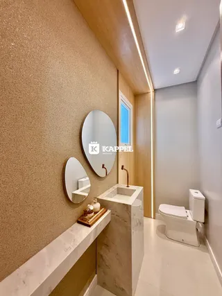 Banheiro moderno com bancada de mármore e espelhos decorativos.