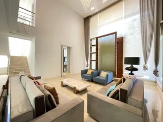Sala de estar ampla com sofá e grandes janelas.