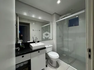 Banheiro moderno com box de vidro e revestimento branco.
