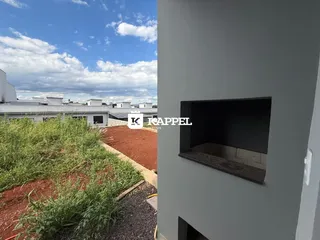 Vista externa de um terreno com vegetação alta e solo avermelhado.