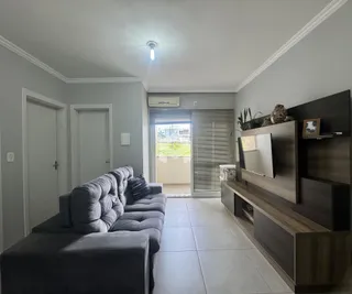 Sala de estar com sofá cinza e piso claro.