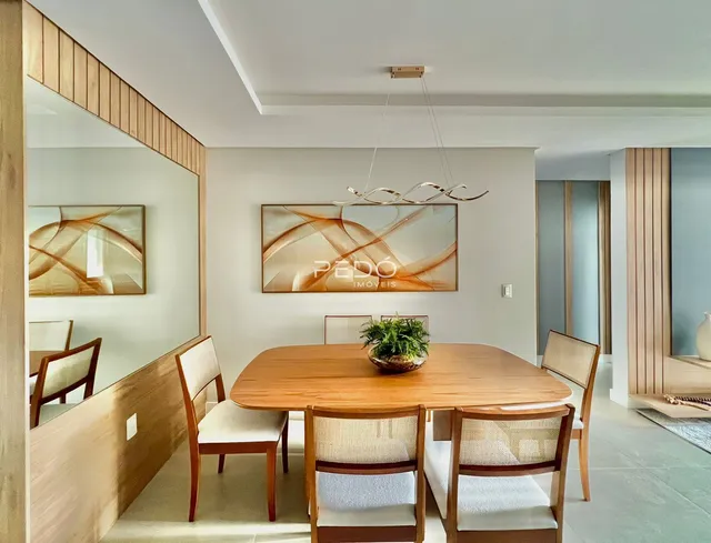 Sala de jantar com mesa de madeira e cadeiras em um ambiente claro.