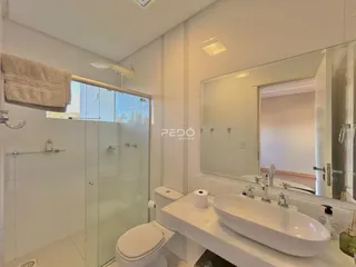 Banheiro moderno com box de vidro e pia branca.