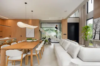 Uma sala de jantar ampla com mesa de madeira e iluminação moderna.