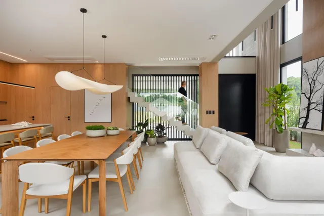 Uma sala de jantar ampla com mesa de madeira e iluminação moderna.