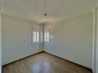 Imagem de uma sala de estar com piso de madeira clara e paredes brancas.