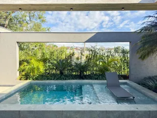 Vista de uma piscina externa com vegetação ao fundo.