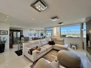 Sala de estar ampla com sofá e vista para o exterior.