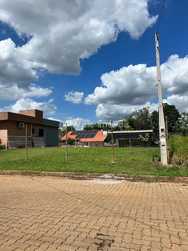 Vista externa de uma propriedade com gramado e cerca.