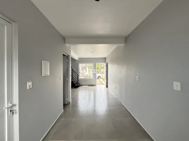 Corredor interno de uma residência com paredes cinzas e piso claro.