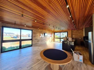 Ambiente interno amplo com piso de madeira e teto de ripas de madeira.